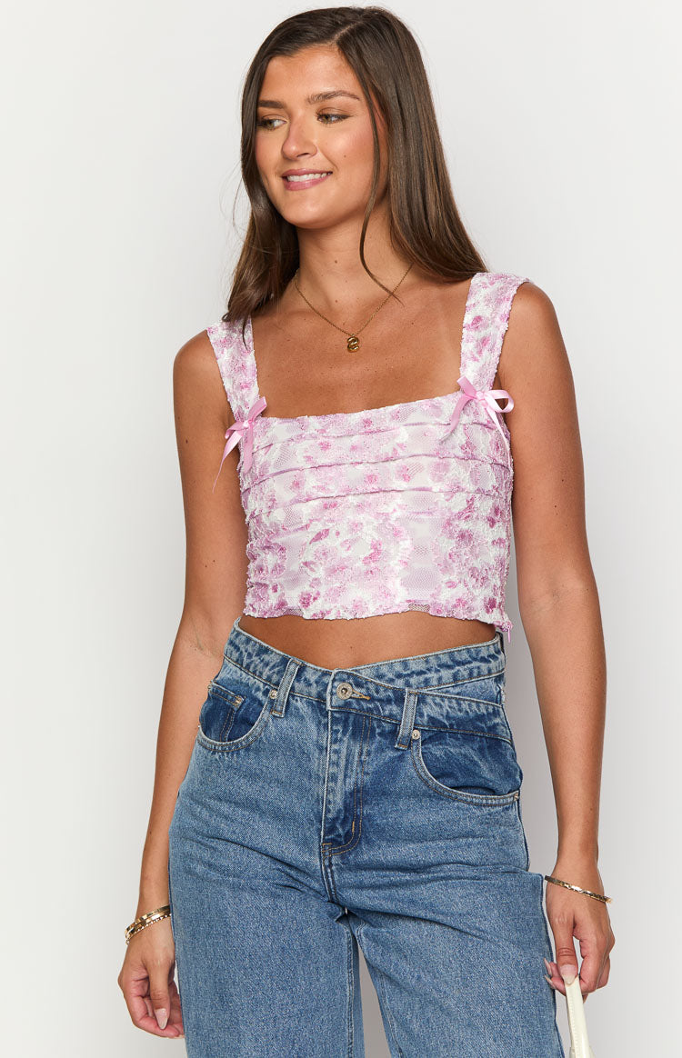 Pink floral lace crop top with a square neckline, wide straps, pink bows, and horizontal pleated front