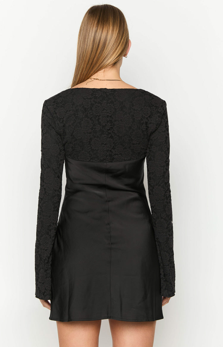 Rear view of a black long sleeve mini dress with a lace upper back and sleeves and a satin skirt