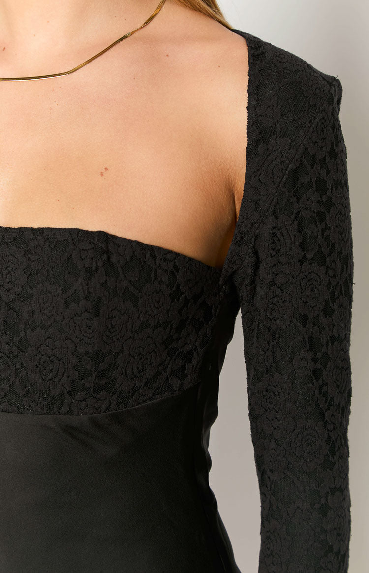 Close-up of the black square neckline with floral lace overlay on the bust and long sleeves of the mini dress