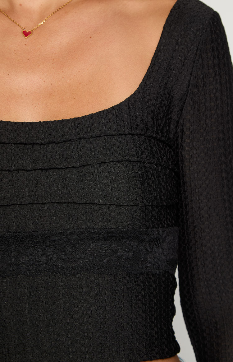 Close-up of the black textured long sleeve top with a square neckline and horizontal ruched detailing