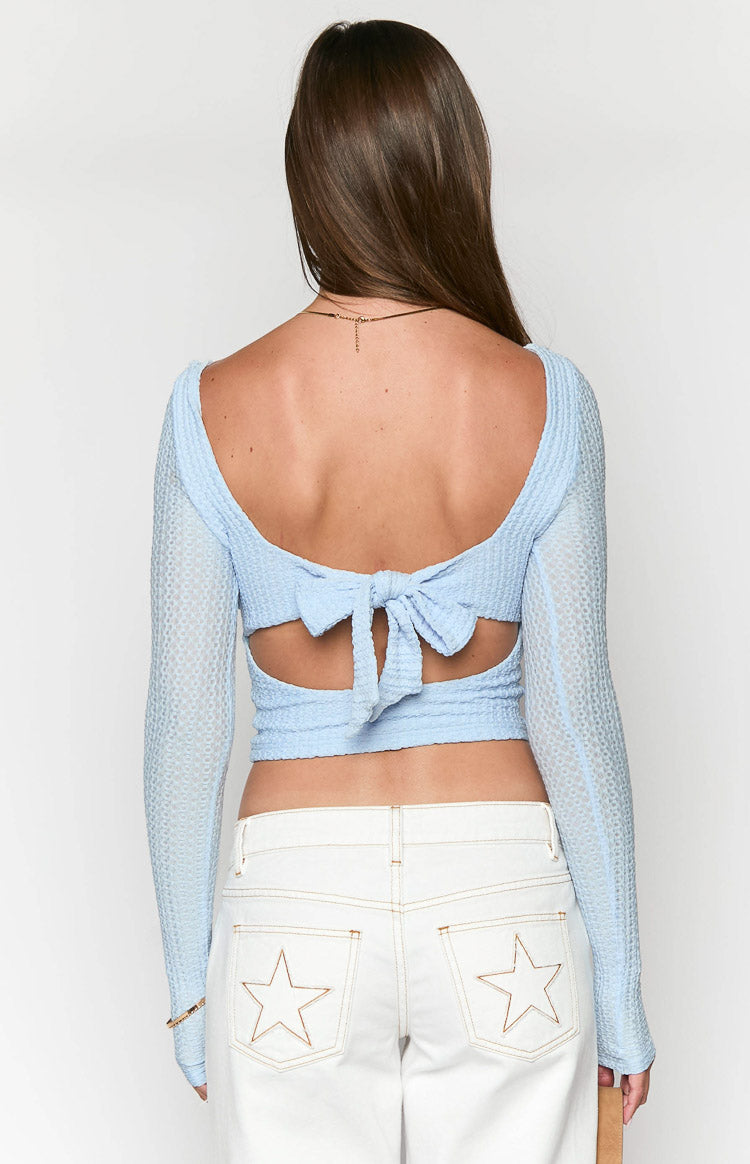 Back view of a light blue textured long sleeve top with a scoop back, large bow tie-back, and waist cutouts