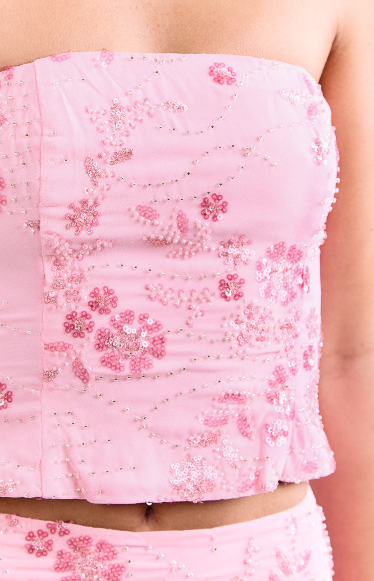 Close-up of the light pink strapless top with intricate floral patterns of pink beads, sequins, and tiny silver beads