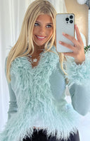 Close-up of the mint green ribbed knit cardigan with shaggy fur trim on the V-neckline and cuffs