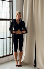 Front view of a black ribbed knit cardigan with a deep V-neck, cropped hem, and fluffy black fur trim on the collar and cuffs