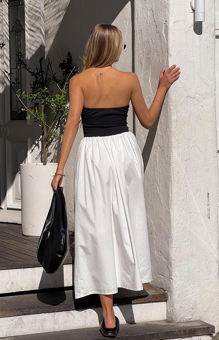 Rear view of a black fitted strapless bodice with a gathered white flowy maxi skirt