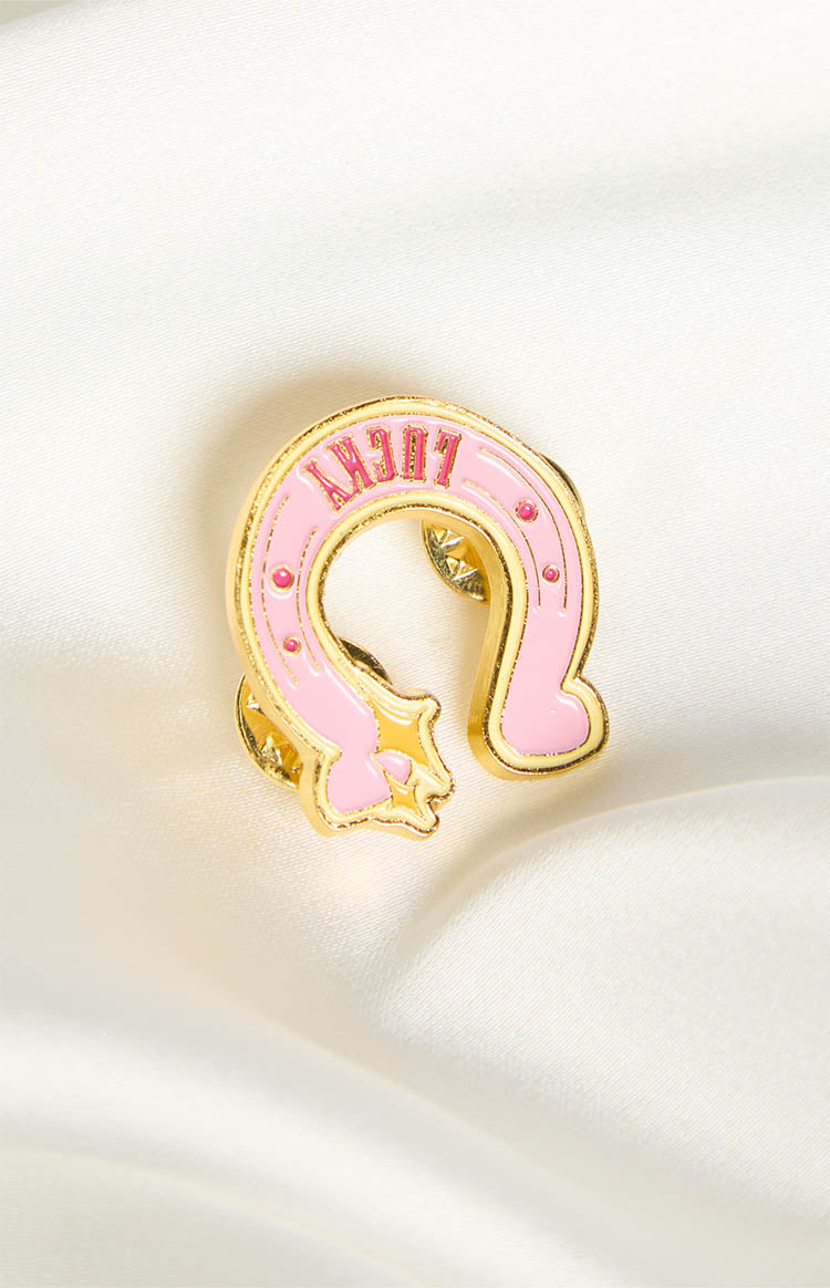 Pink horseshoe pin with gold trim, "LUCKY" text, and small gold stars and pink dots