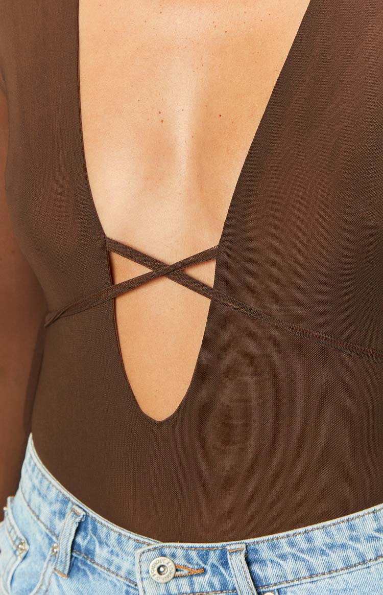Close-up of the brown mesh bodysuit showing the deep V-neckline with criss-cross strap detail