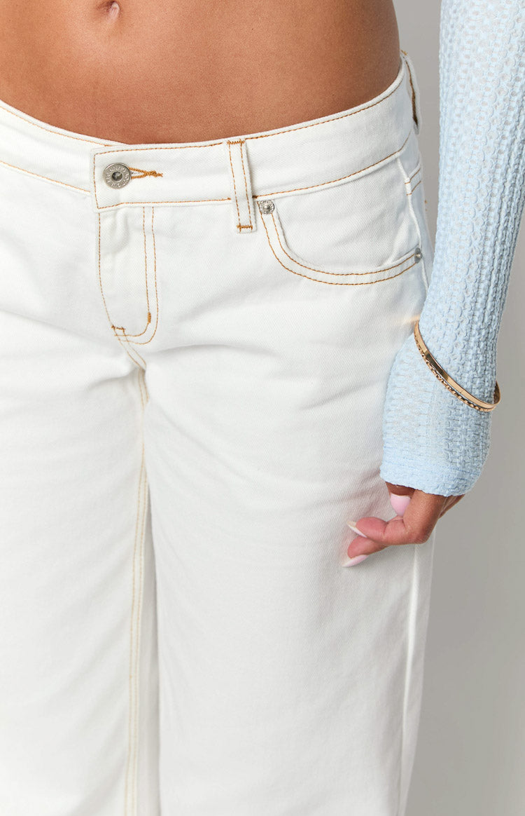 Close-up of the white low-rise denim jeans showing the waistband, button closure, and tan contrast stitching