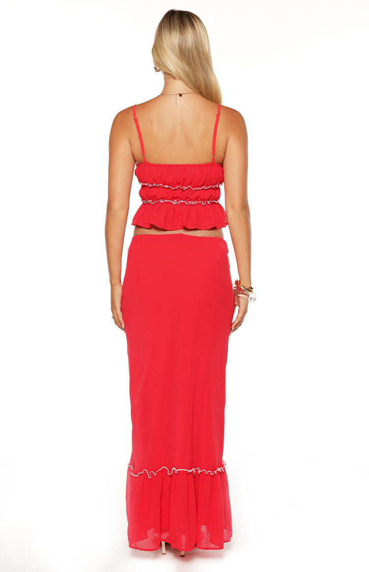 Rear view of a red crop top with thin spaghetti straps and multiple shirred tiers with white contrast stitching