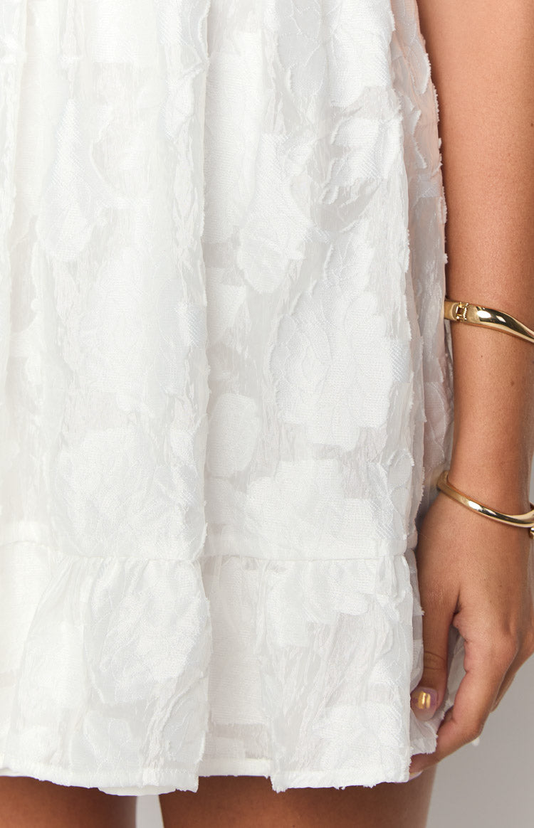Textured white mini dress fabric with a subtle floral pattern and a ruffled tier at the hem