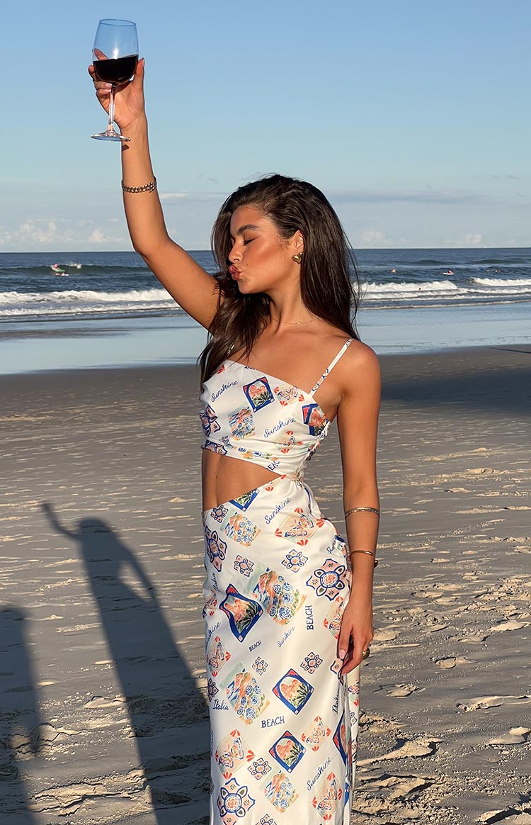 Front view of a white satin maxi dress with colourful Italia print, featuring a side cutout and thin straps