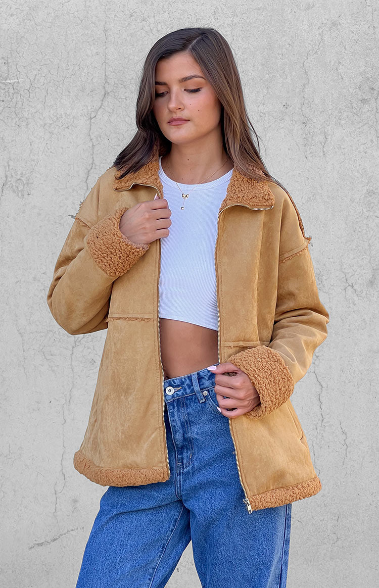 Front view of a brown suede fur jacket, partially unzipped, with exposed seams and fur trim on collar, cuffs, and hem
