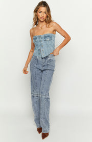 Front view of a mid-wash denim strapless button-front top with chest pockets and a curved hem