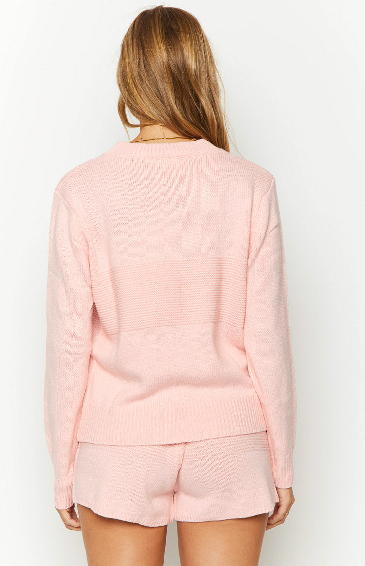 Rear view of a pink long sleeve knit top with horizontal textured knit bands across the back and ribbed hem
