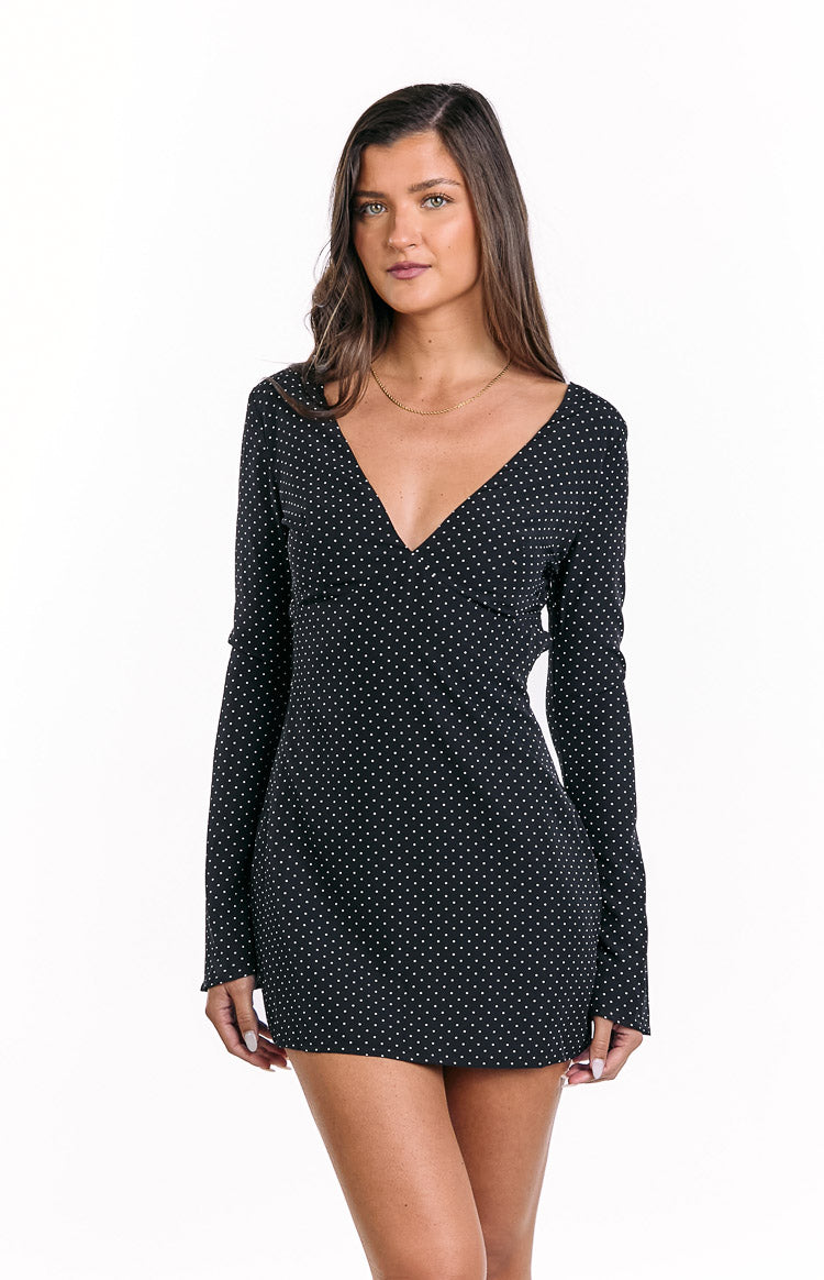 Black polka dot mini dress featuring a deep V-neckline and fitted long sleeves