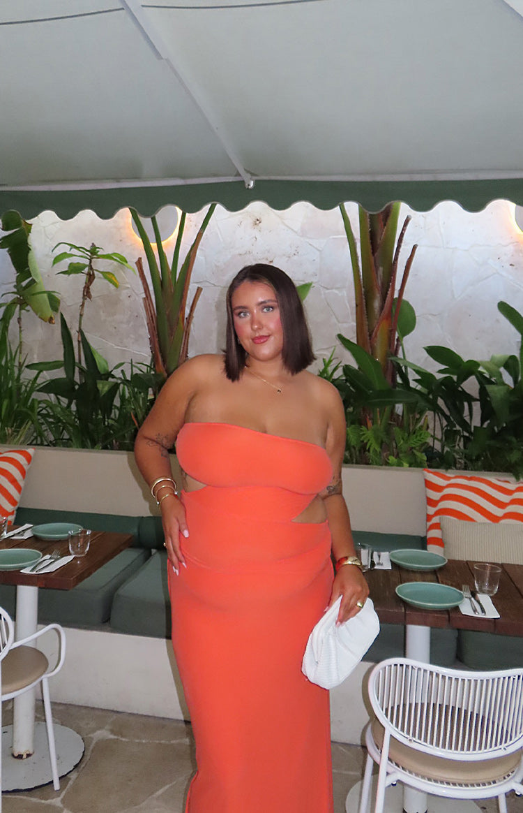 Front view of an orange strapless maxi dress with side cutouts at the waist