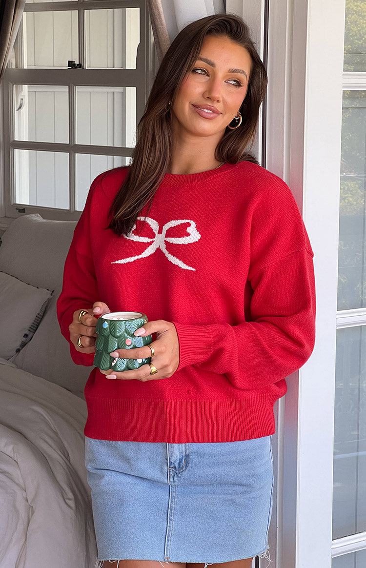 Front view of a red crew neck sweater with a white bow graphic, ribbed cuffs and hem