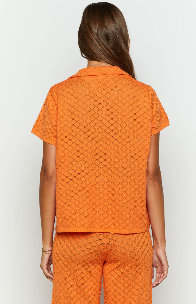Rear view of the orange knit top with a collared neckline, short sleeves, and an all-over open diamond knit pattern
