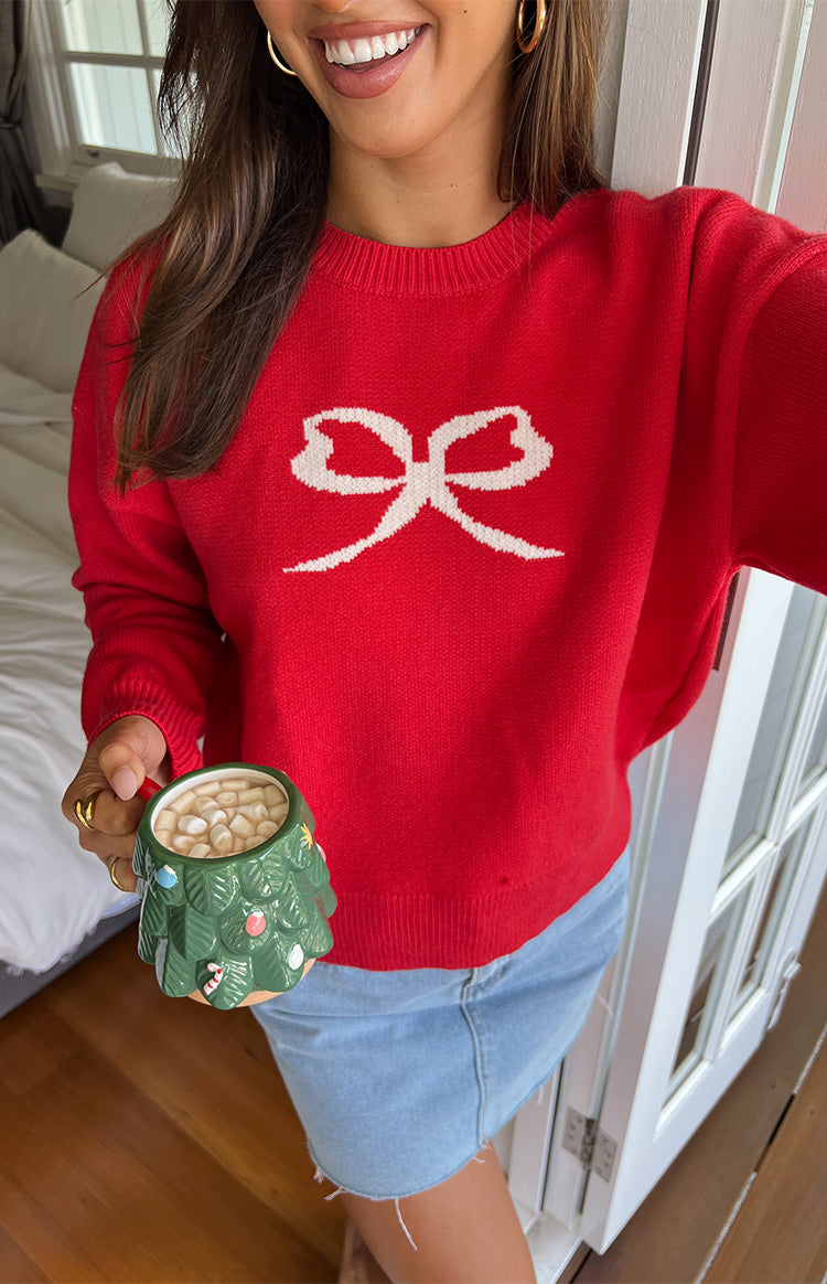 Red knit sweater with a large white bow graphic, ribbed crew neck, cuffs, and hem