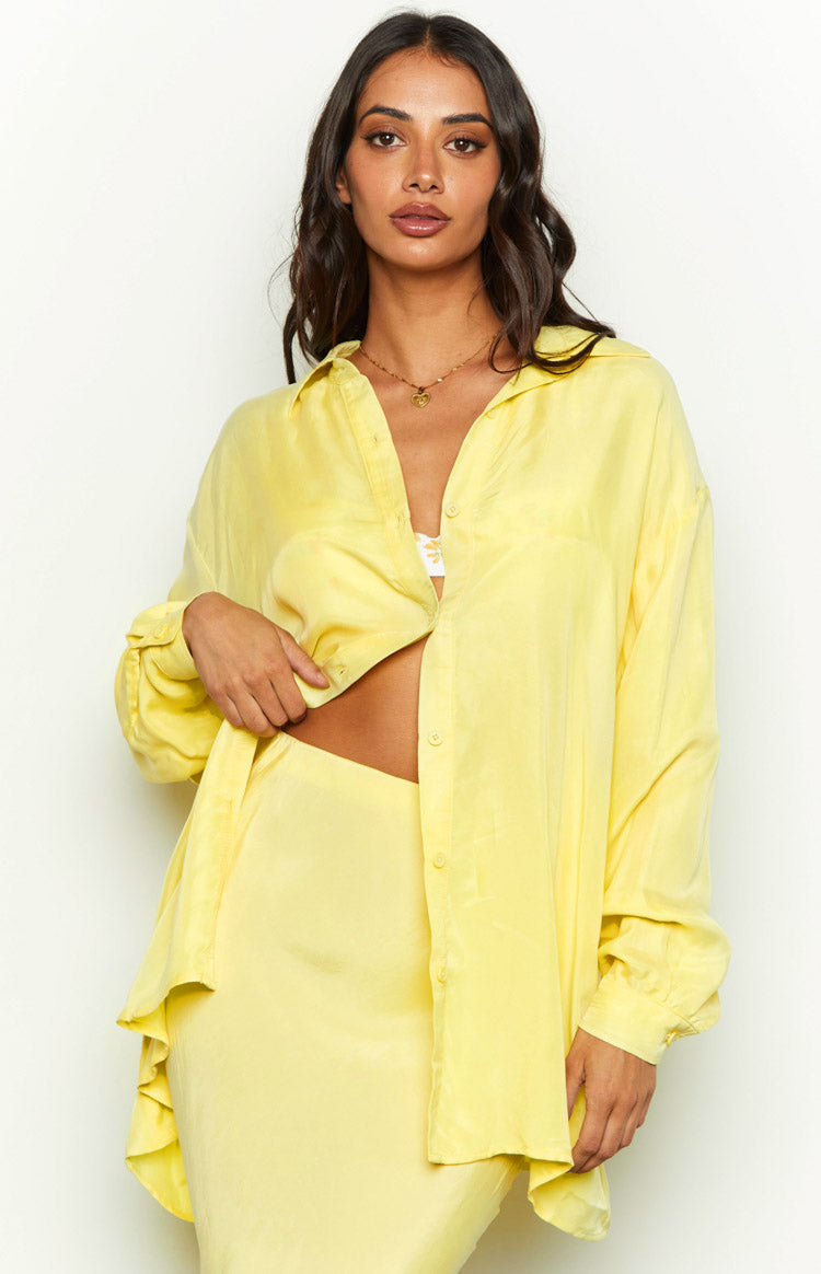 Yellow cupro button-up shirt worn open and tied at the front, showing the soft drape of the fabric