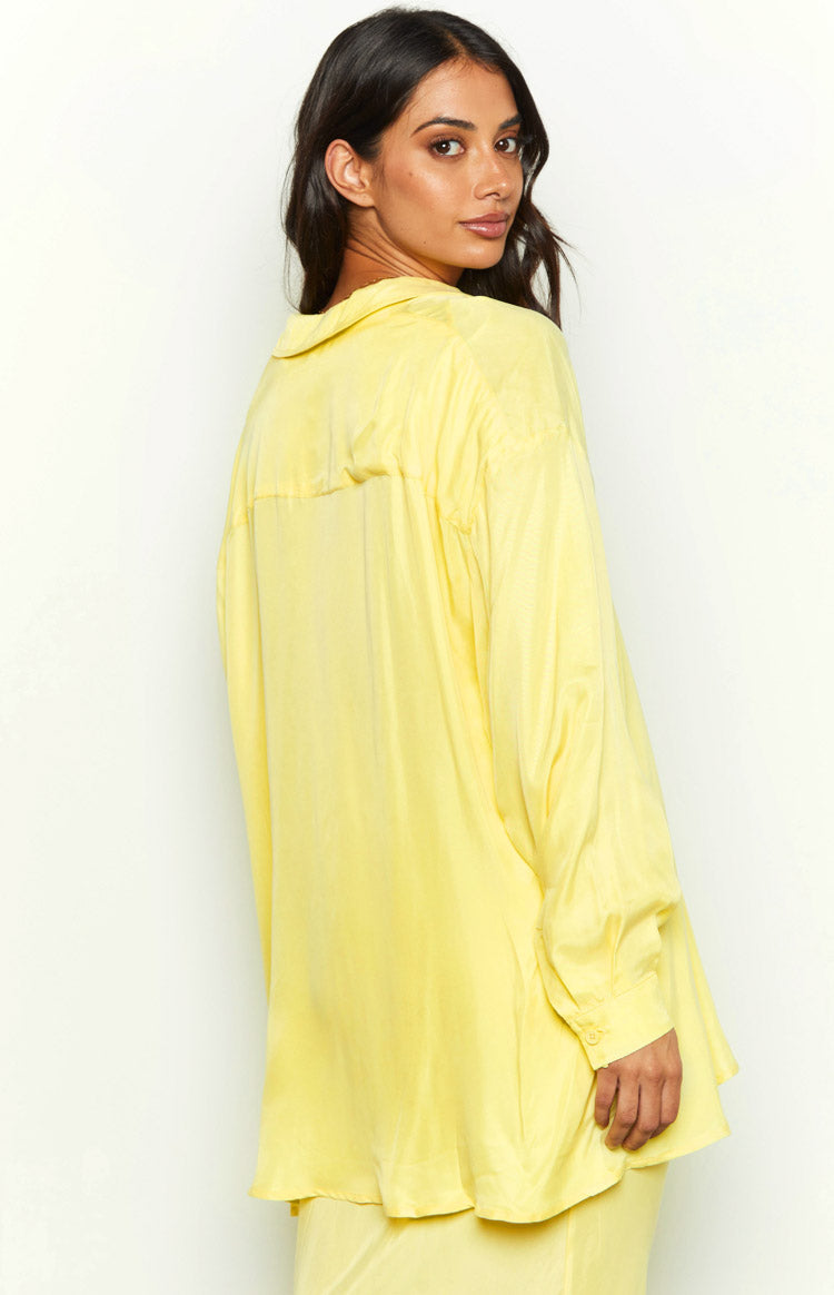 Angled rear view of the yellow cupro button-up shirt with a relaxed fit and long cuffed sleeves