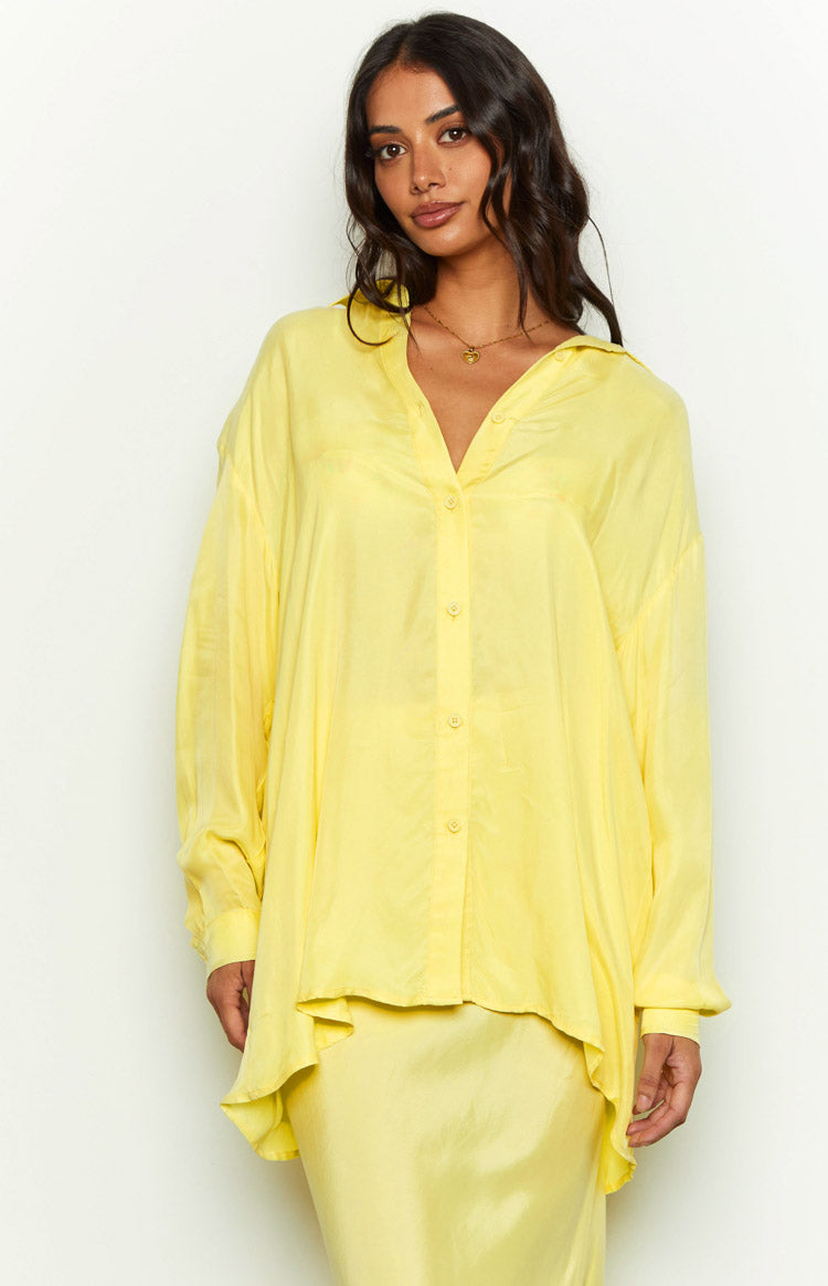 Front view of a yellow cupro button-up shirt with an open collar, long sleeves, and a relaxed, curved hem
