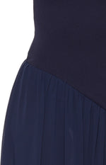 Close-up of the navy maxi dress showing the diagonal seam where the fitted bodice joins the gathered skirt