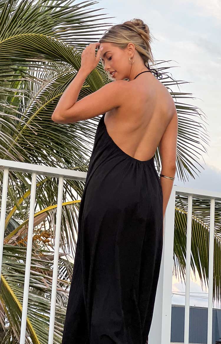 Rear view of a black halter neck maxi dress showing the low open back and tie detail