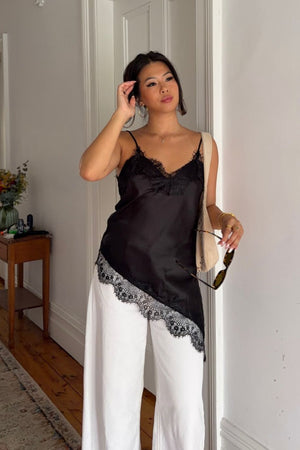 Beginning Boutique Ziva Black Satin Lace Trim Asymmetrical Top black satin top with spaghetti straps and asymmetrical lace tr