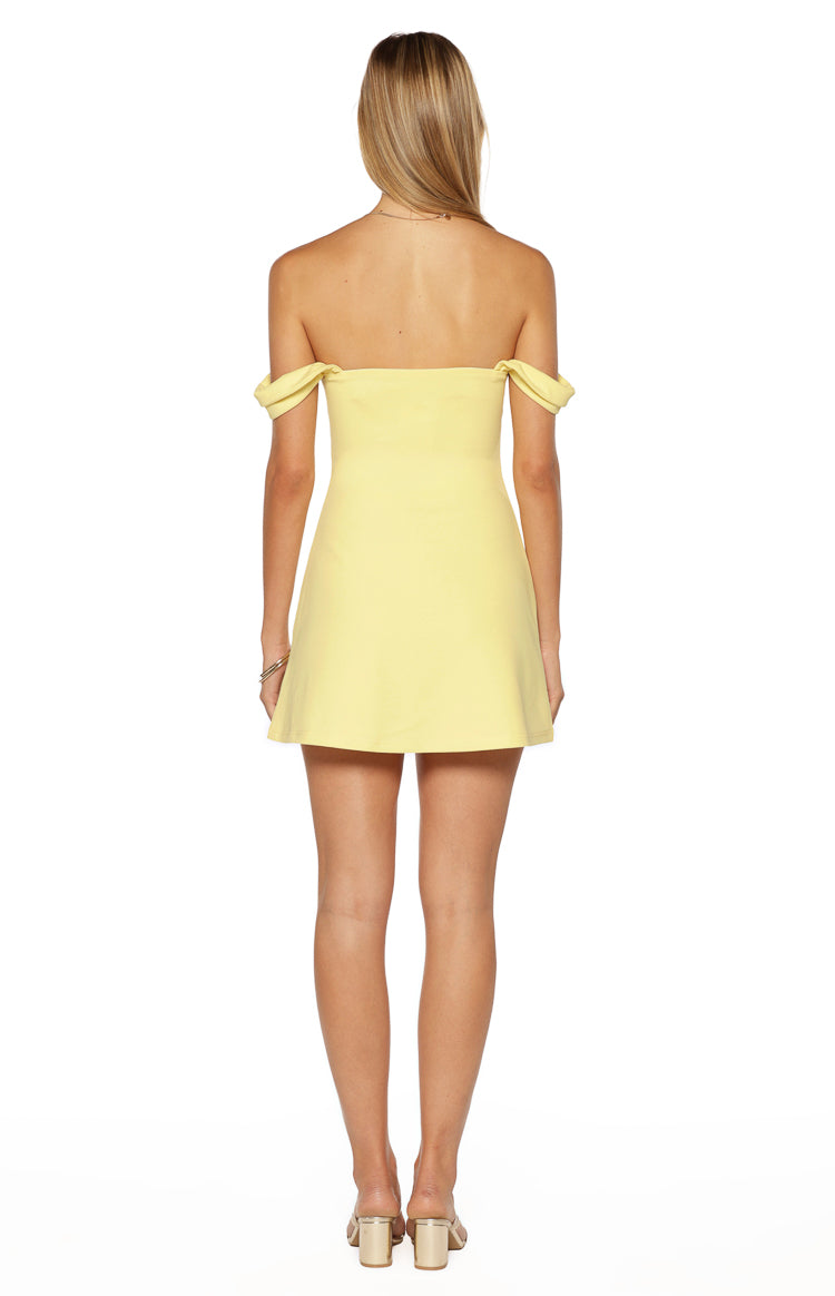Rear view of a yellow crepe off-the-shoulder mini dress with short draped sleeves and a subtle A-line skirt