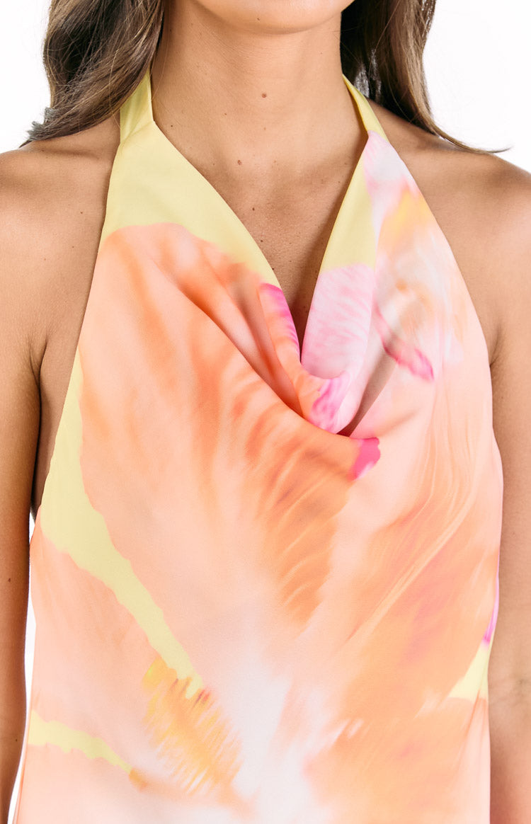 Close-up of the draped cowl neckline of a yellow mini dress with orange and pink hibiscus floral print