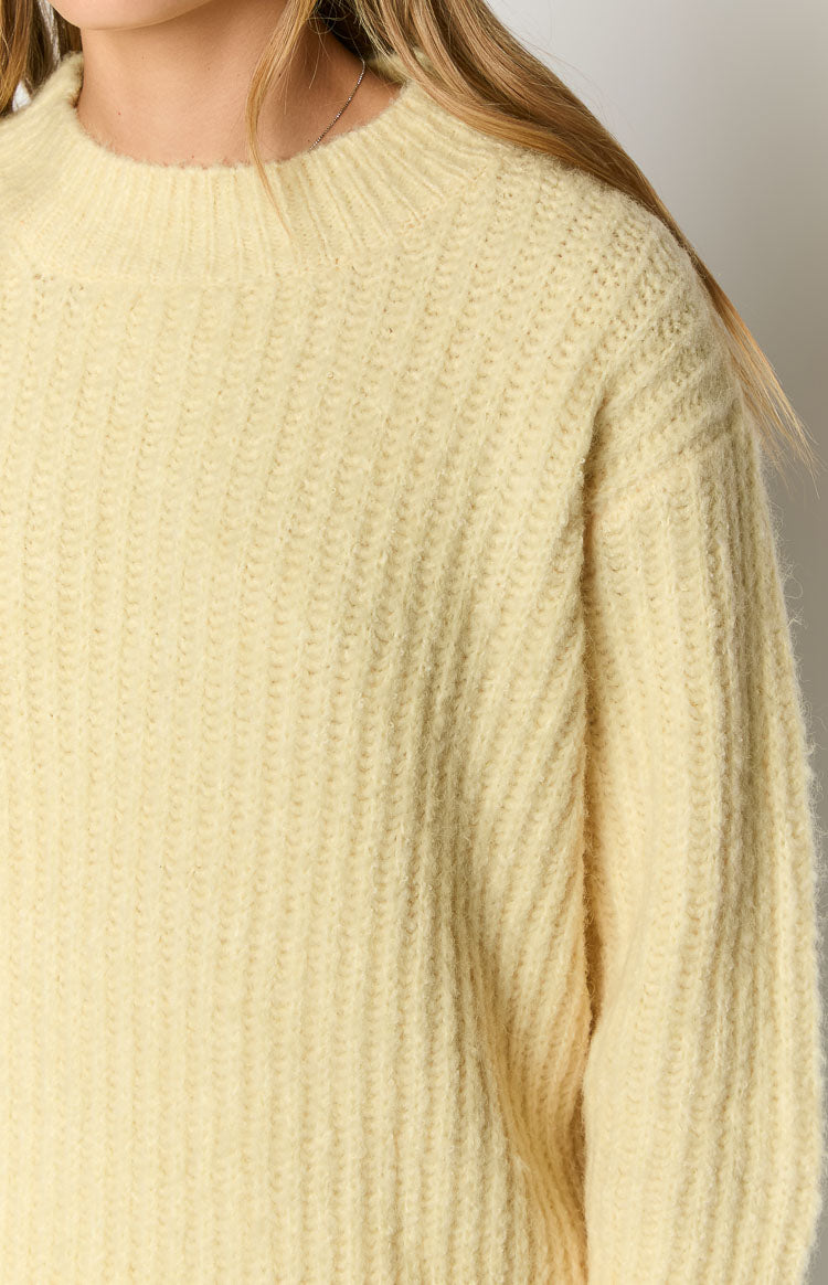 Close-up of the yellow ribbed knit oversized sweater showing the crew neckline and dropped shoulder