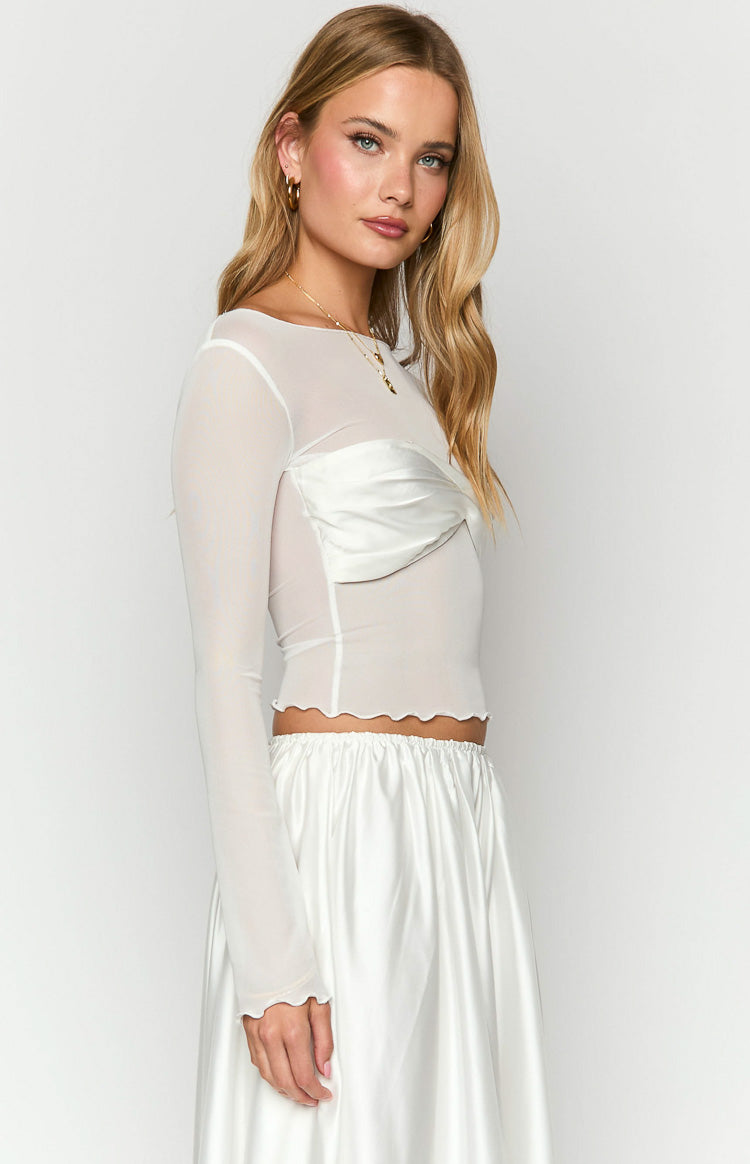 Side view of a white sheer mesh long sleeve top with a satin twisted bust detail and lettuce hem