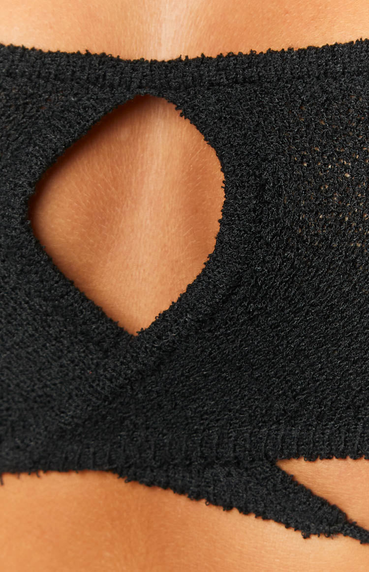 Close-up of the black knit crop top's irregular cutout and textured fabric