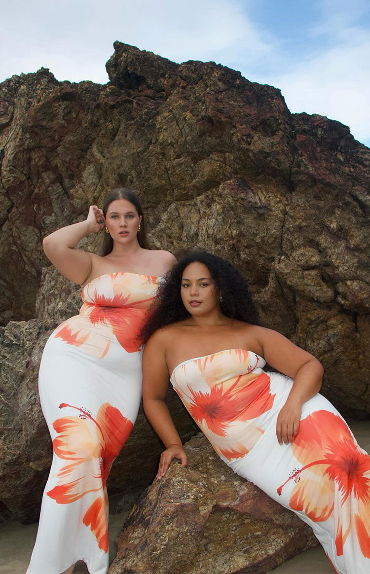 Two white strapless bodycon maxi dresses with vibrant orange and red hibiscus floral print