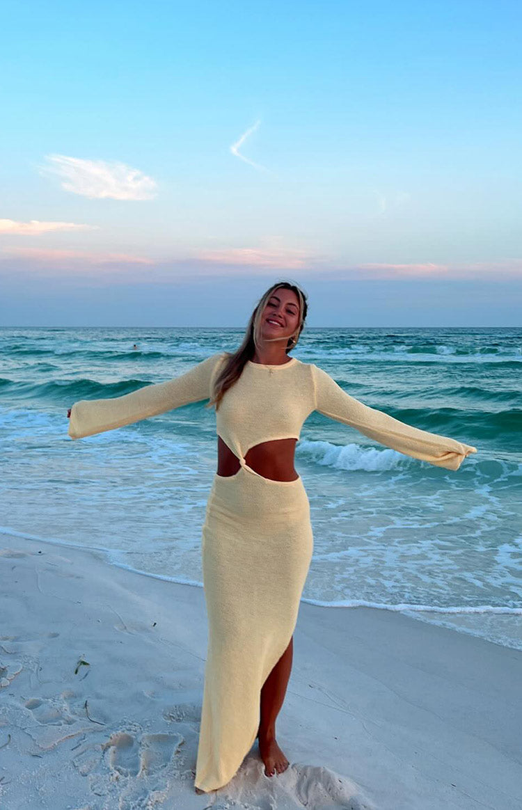 Full length view of a yellow knit maxi dress with long sleeves, waist cutouts, and a high side slit