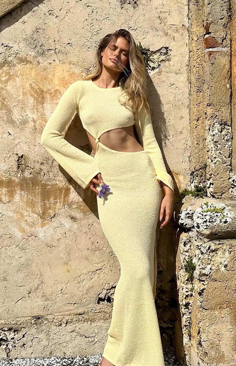 Angled view of a yellow long sleeve knit maxi dress featuring side cutouts and a textured knit