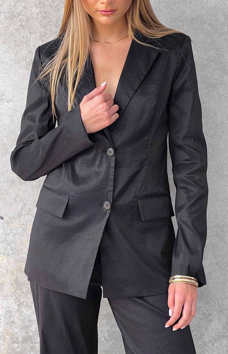 Detail shot of the black blazer's subtle textured fabric, notched lapels, and two-button front