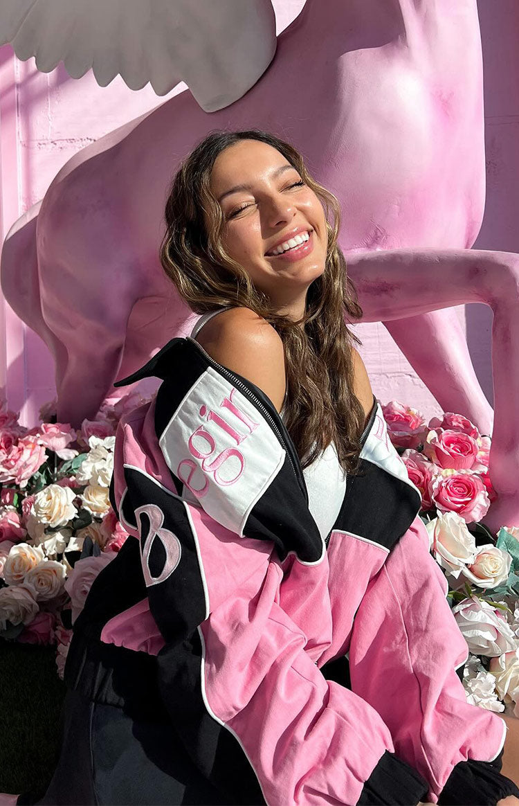 Close-up of the pink, black, and white bomber jacket with embroidered 'Begin' and 'B' details on the sleeves