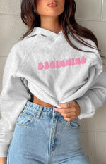 Close-up of the grey marl hoodie with pink BEGINNING bubble text and cropped ribbed hem
