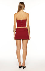 Rear view of the burgundy mini skirt with subtle ruched detailing on the sides