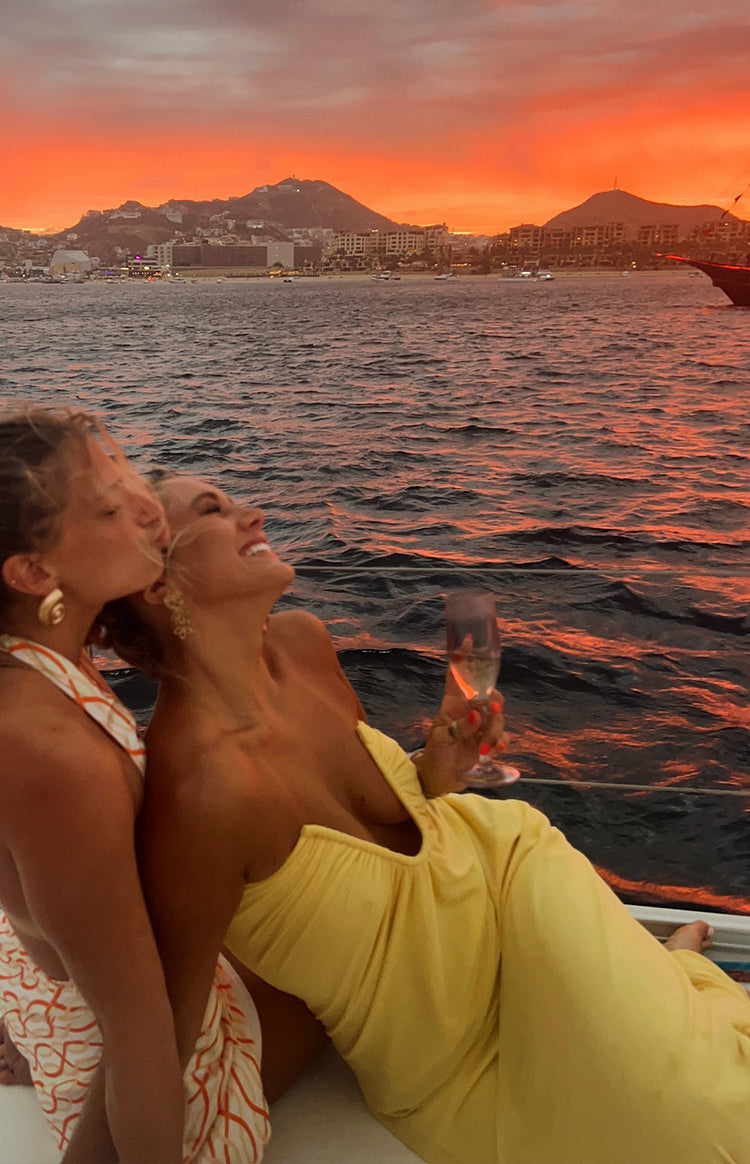 Side view of a yellow strapless maxi dress with a gathered sweetheart neckline and flowy skirt