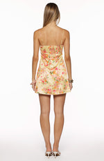 Rear view of a yellow floral mini dress with a smocked back and thin spaghetti straps