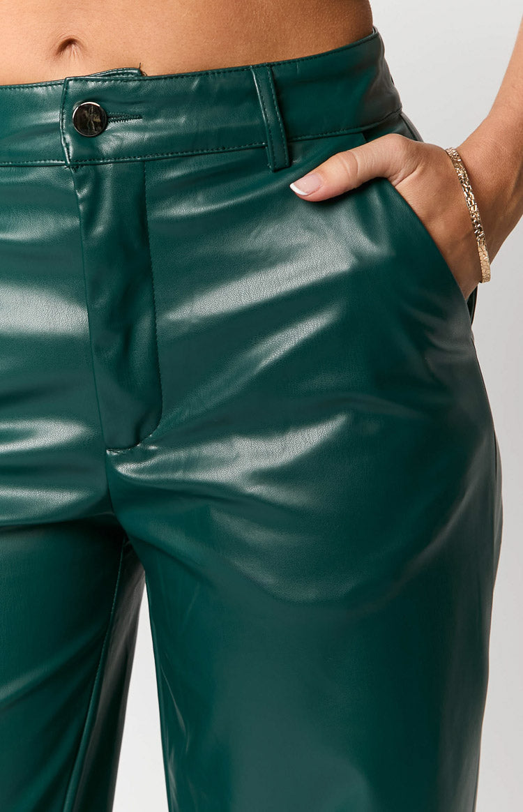Close-up of the forest green PU pants showing the waistband, silver button, and side pockets