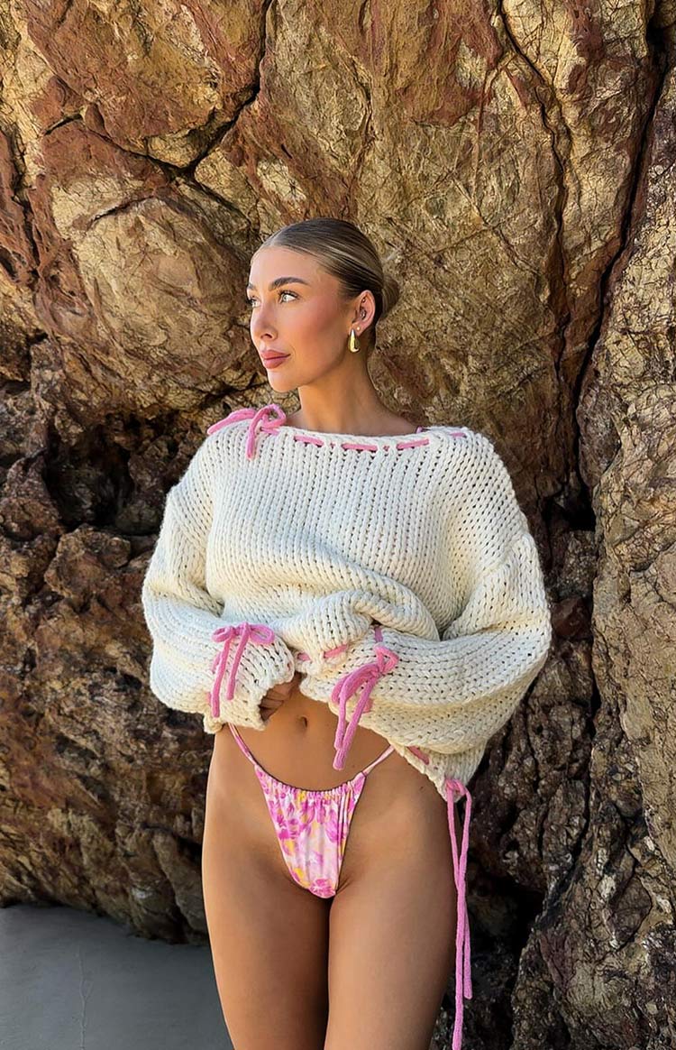 Cream oversized chunky knit sweater with pink tie details at the neckline, cuffs, and hem