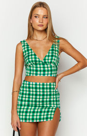 Front view of a green and cream check crop top with a deep V-neckline and wide shoulder straps
