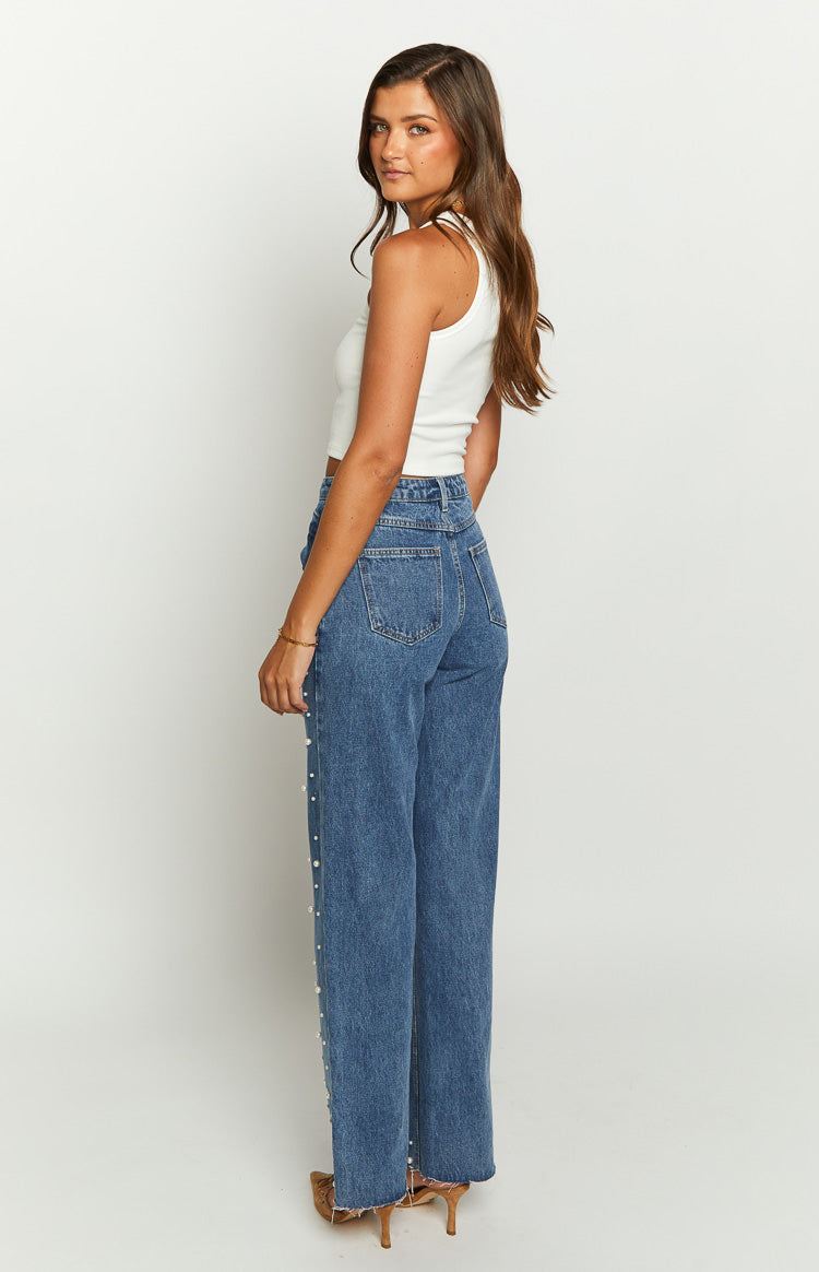 Side view of mid wash blue high waisted jeans with pearl detailing down the outer seams