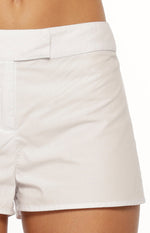 Close-up of the flat waistband, side seam, and clean hem of white low-rise shorts