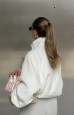 Back view of a cream funnel neck sports jacket with a relaxed fit, dropped shoulders, and horizontal seam