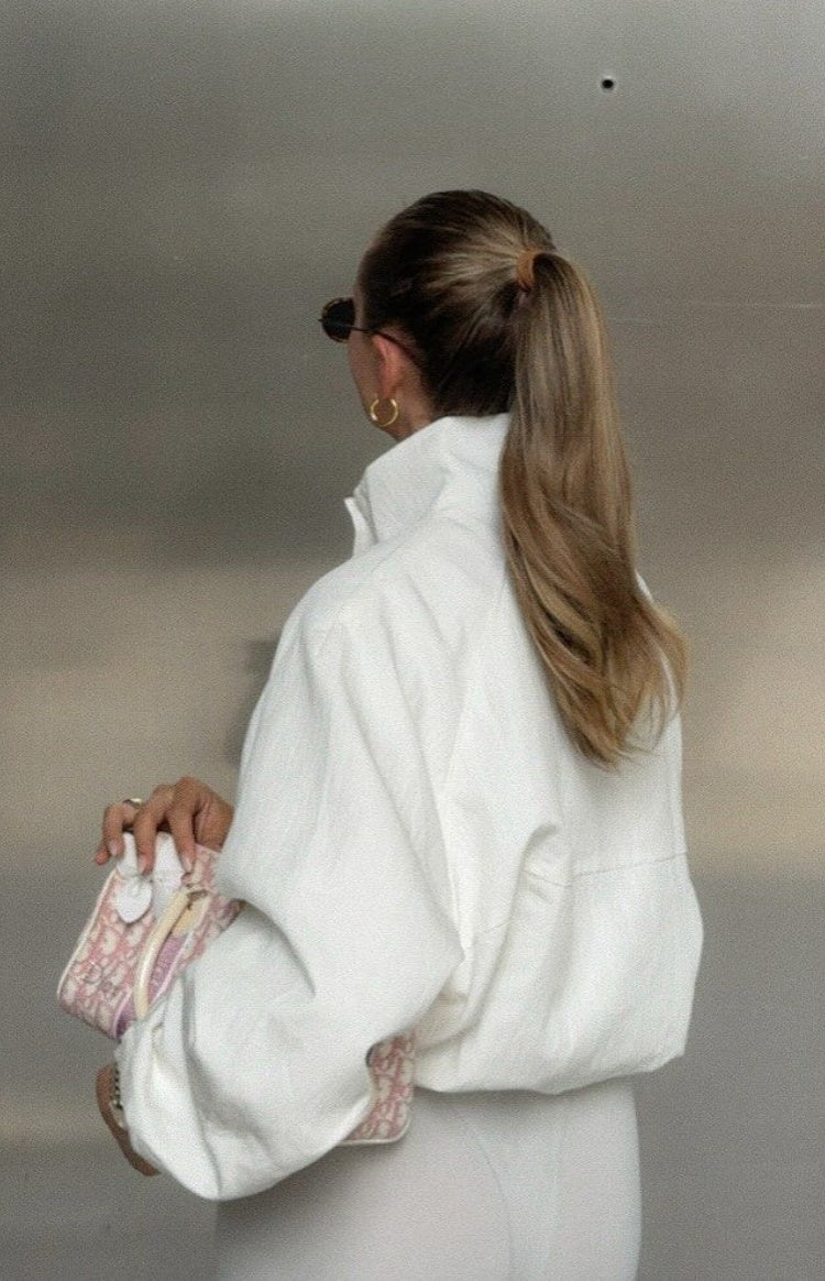 Back view of a cream funnel neck sports jacket with a relaxed fit, dropped shoulders, and horizontal seam